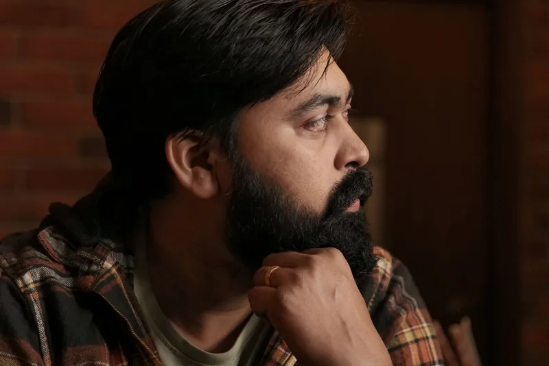 Profile of a South Asian man with neatly shaped dark hair and a beard