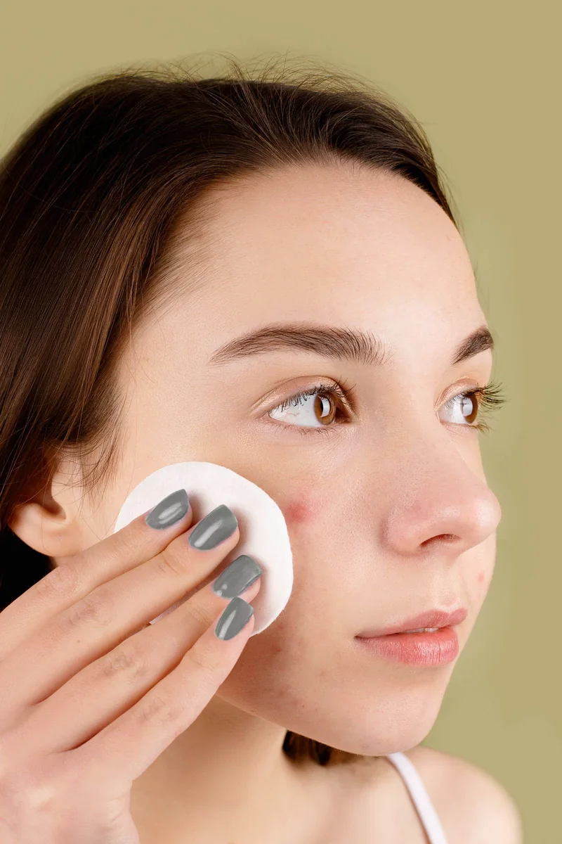 Woman gently cleansing her face with a fresh cotton pad